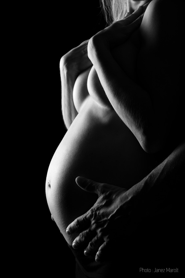 Nosečnica s partnerjem - detajl - nosečnični trebušček ki ga objemajo partnerjeve roke